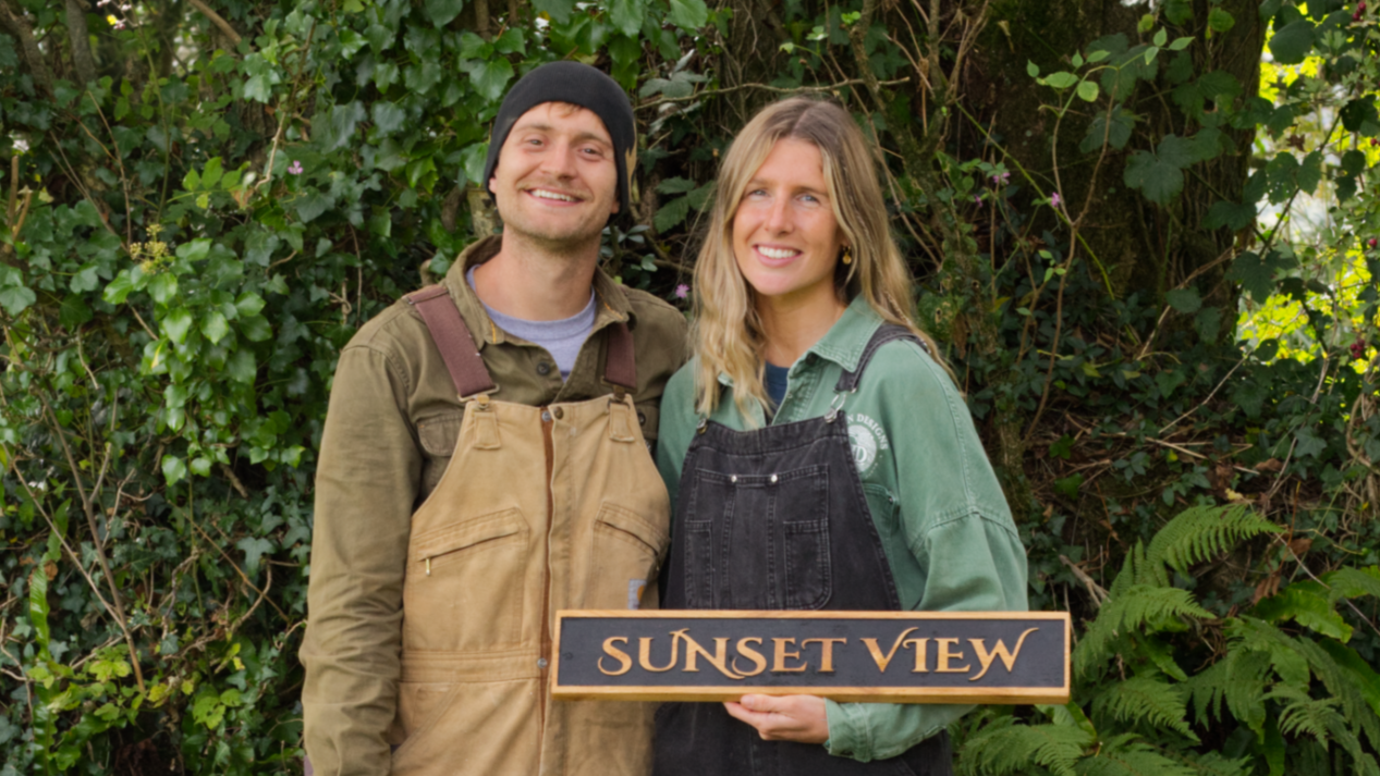 Two people holding wooden signs with text in a natural setting