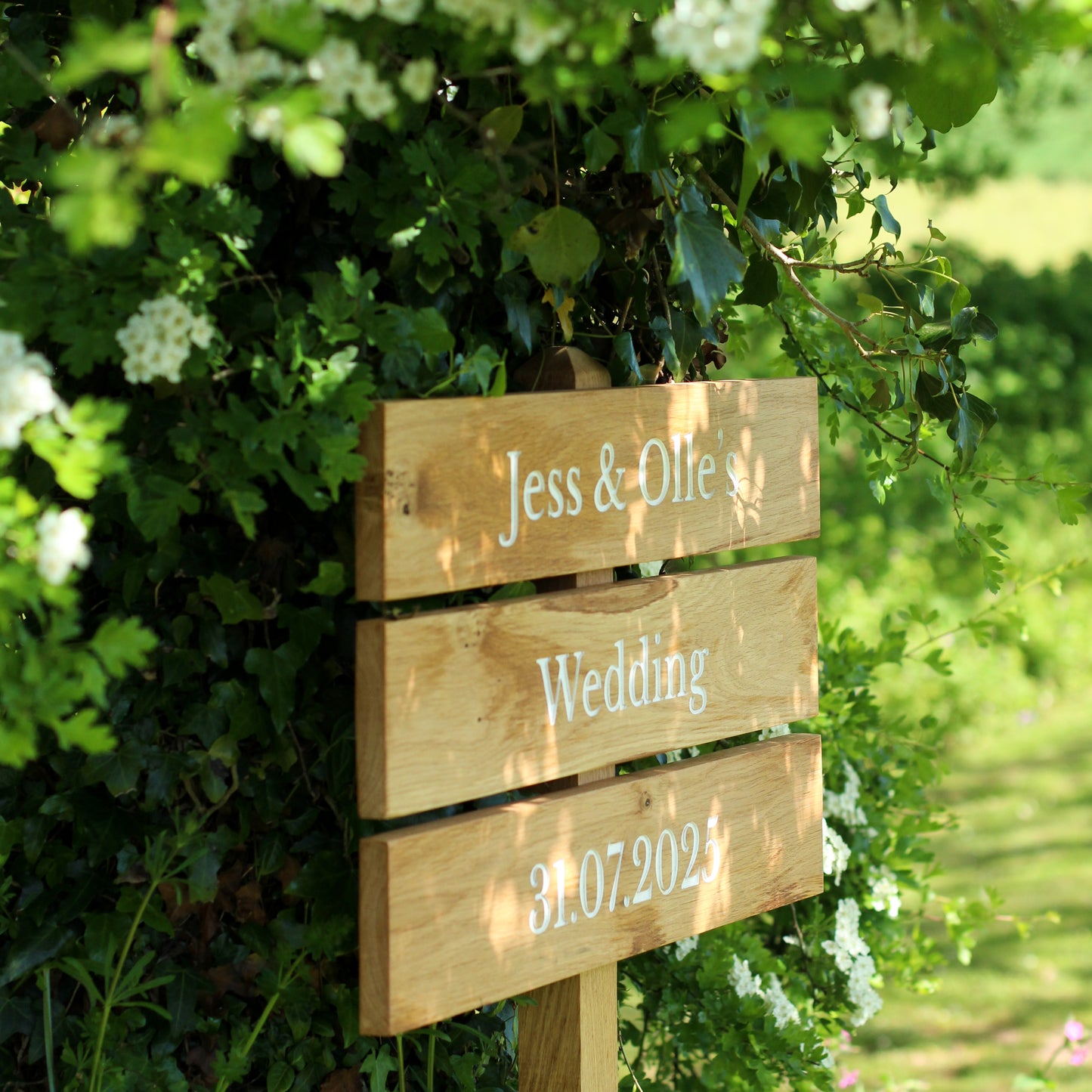 Wooden wedding sign with names and date in a garden setting