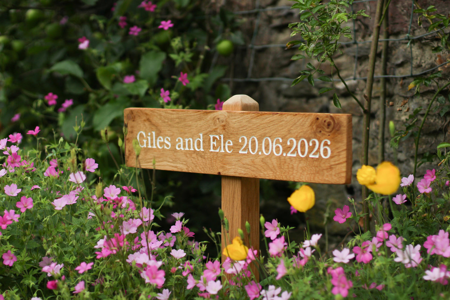 Wooden sign with wedding date in a garden setting