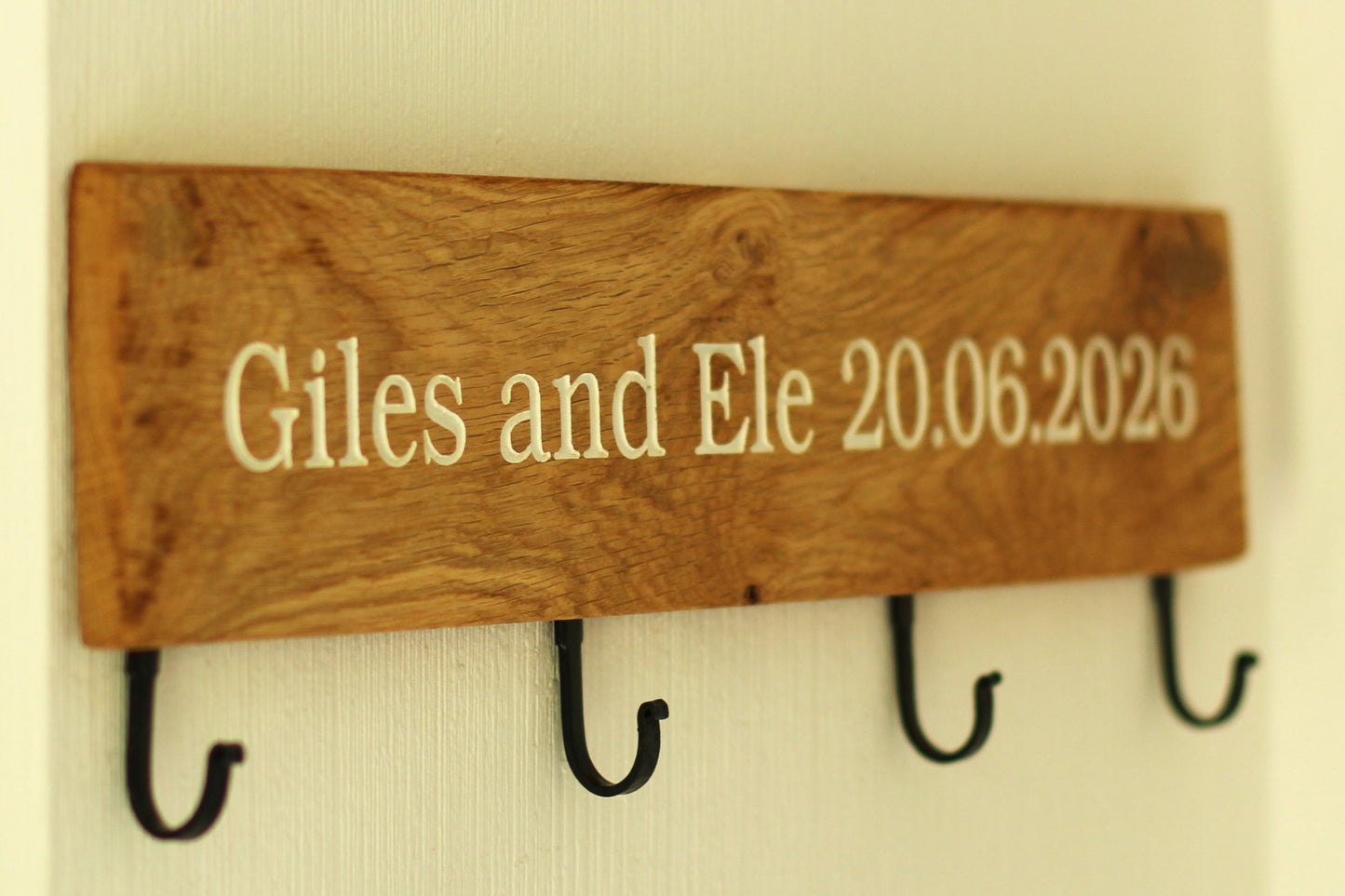 Wooden plaque with engraved text and hooks on a plain background