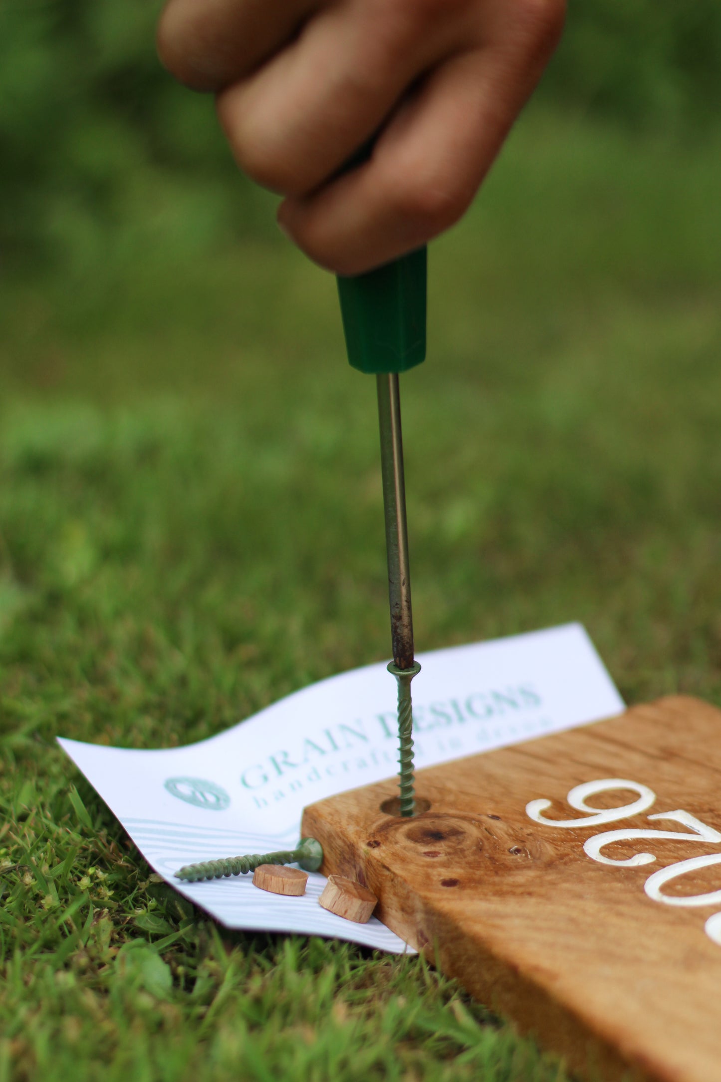Person using a screwdriver on a wooden block with a blurred background