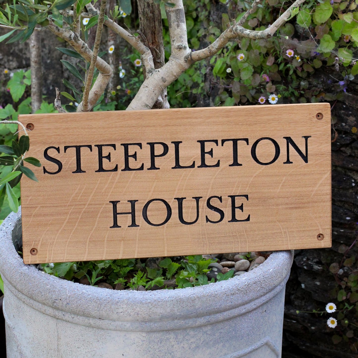 Wooden sign with 'STEEPLETON HOUSE' text in a garden setting