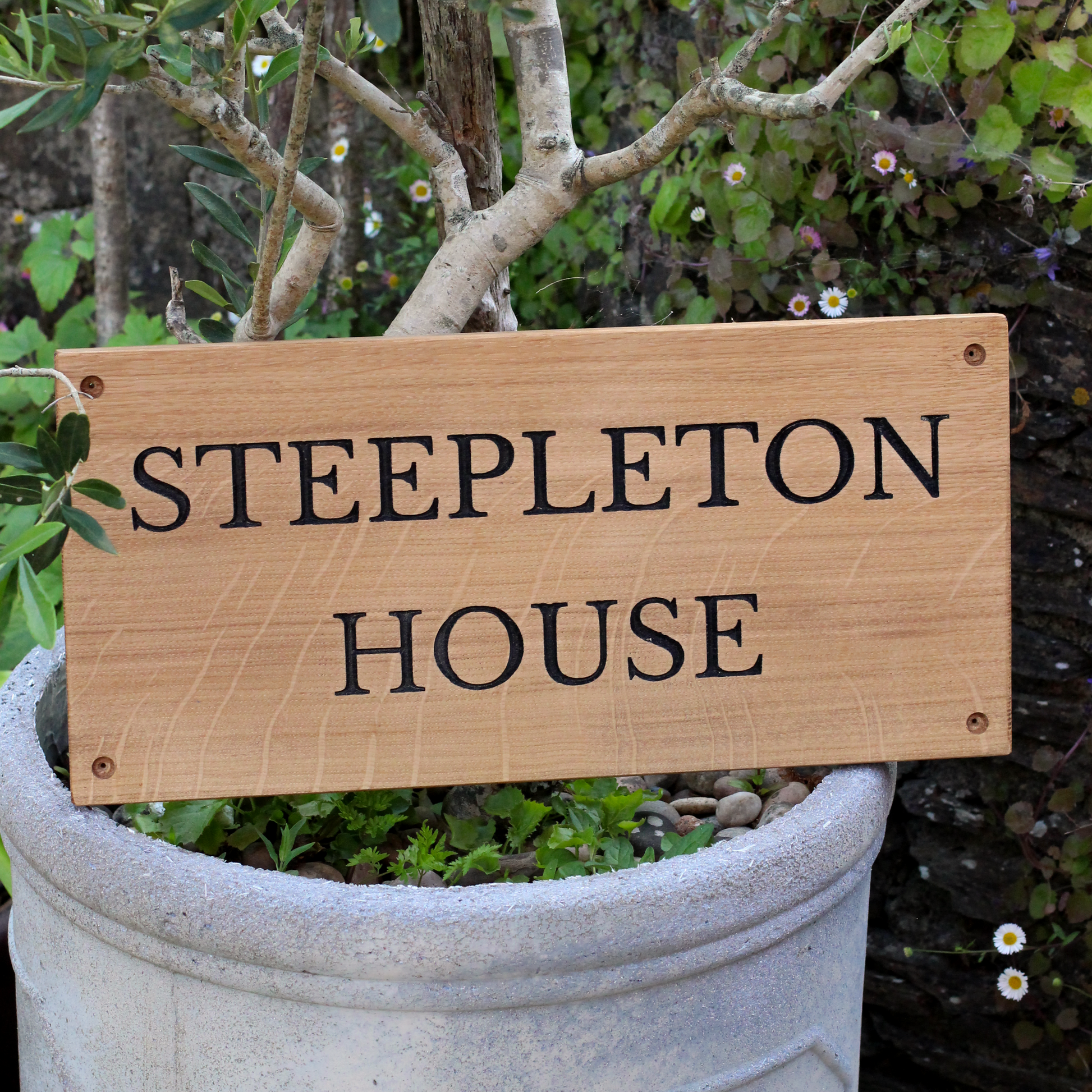 Wooden sign with 'STEEPLETON HOUSE' text in a garden setting