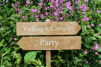 Wooden Wedding Sign saying "Parking & Camping" and then "Part" in from on red campion