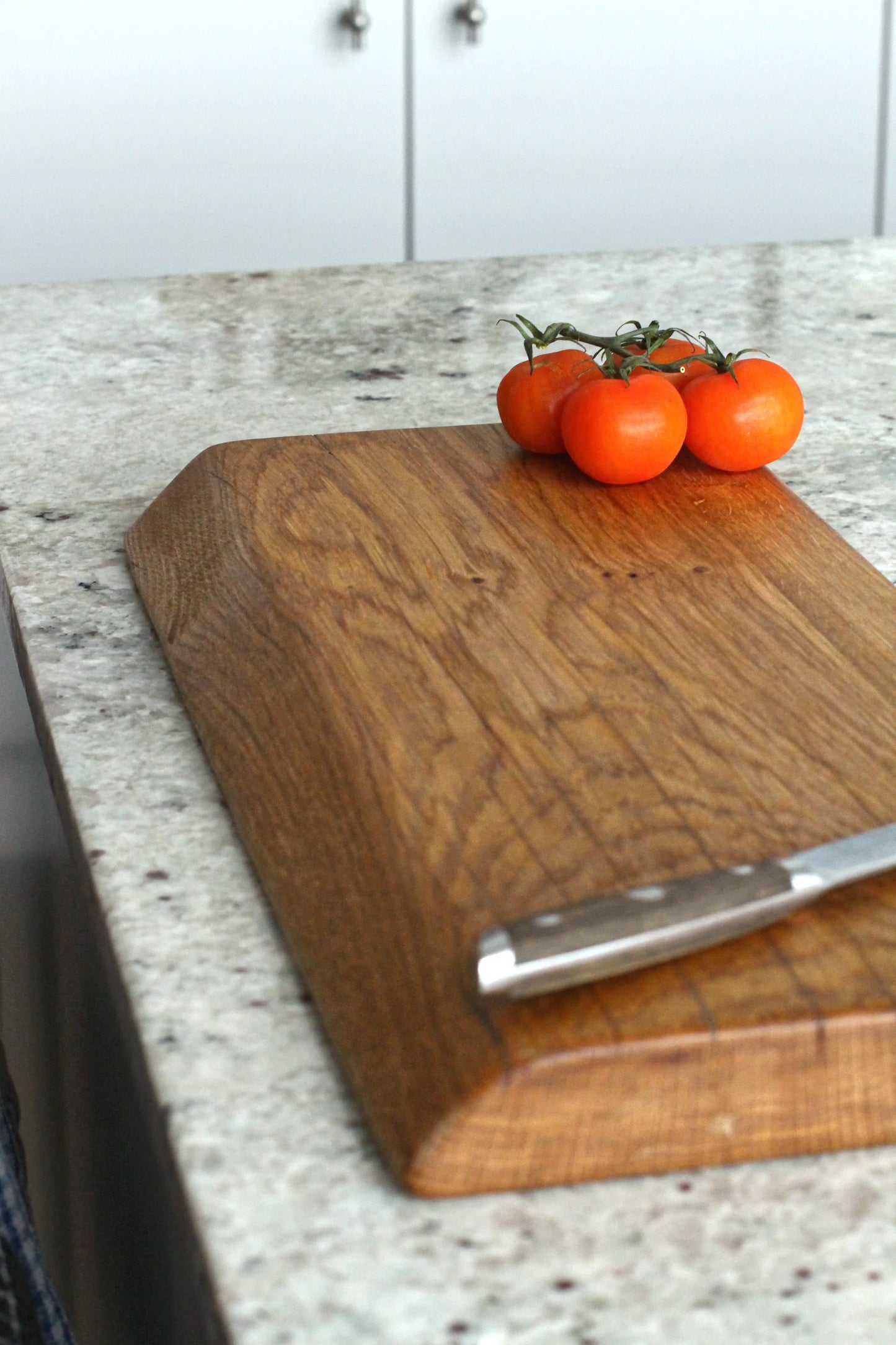 Wooden cutting board on a kitchen counter with tomatoes