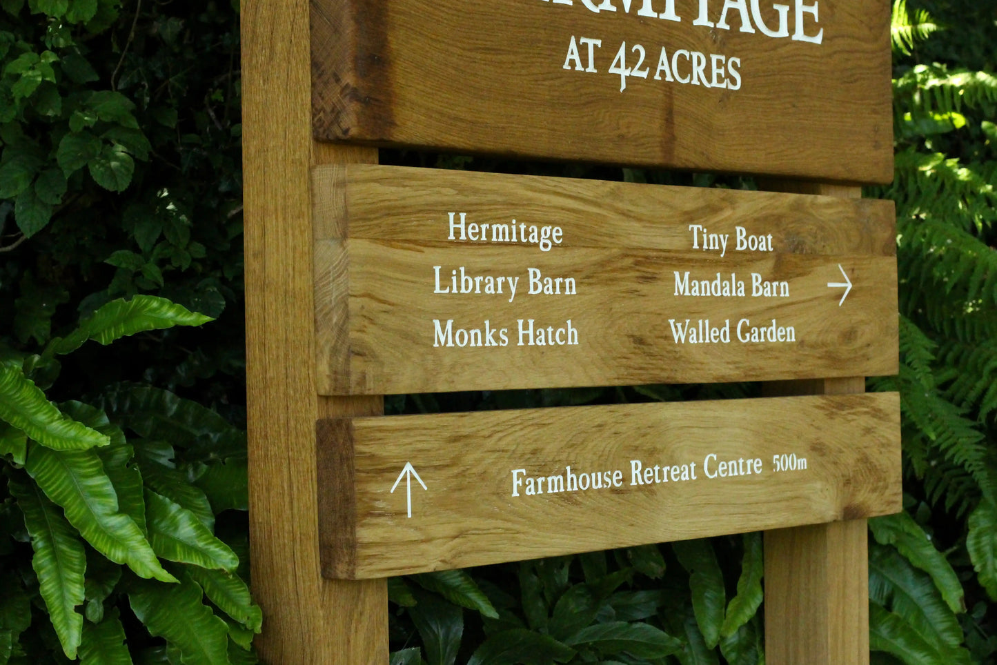 Wooden sign with directional information against a green foliage background