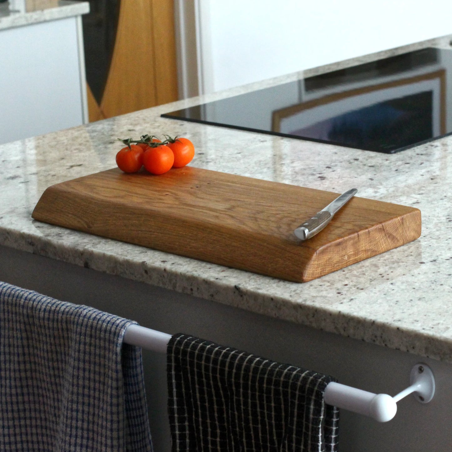 Wooden cutting board with tomatoes and a knife on a kitchen counter