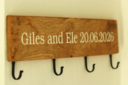 Wooden plaque with engraved text and hooks on a plain background