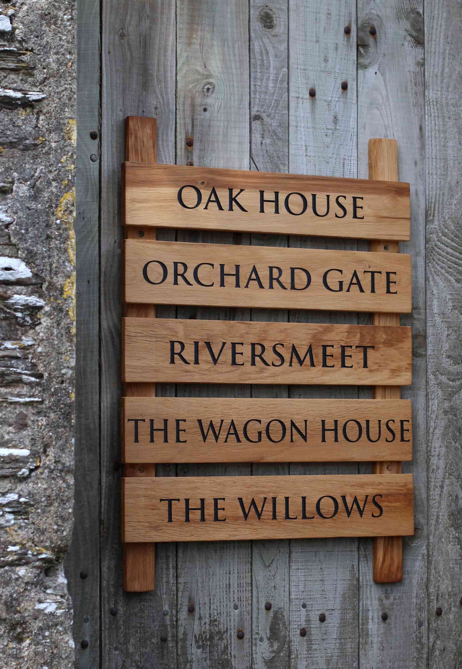 Wooden sign with engraved house names against a wooden background